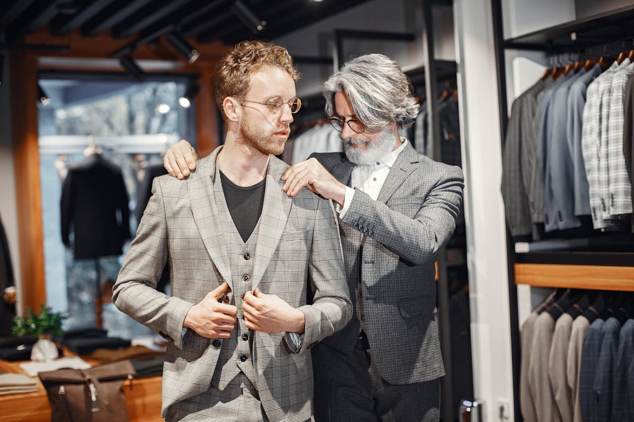 digital A tailor adjusts a suit for a client in a stylish boutique setting.